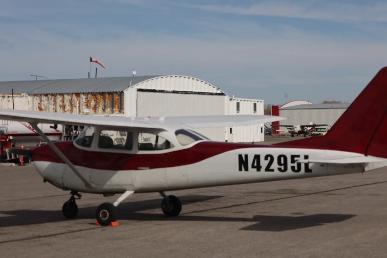 Red and white Cessna 172 side profile at the hangar