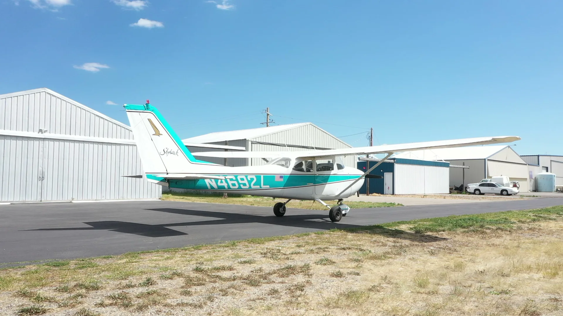 Aerial side view of a Cessna Skyhawk by the hangars
